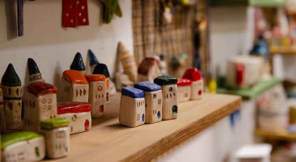 Small ceramic house figurines along a wooden shelf
