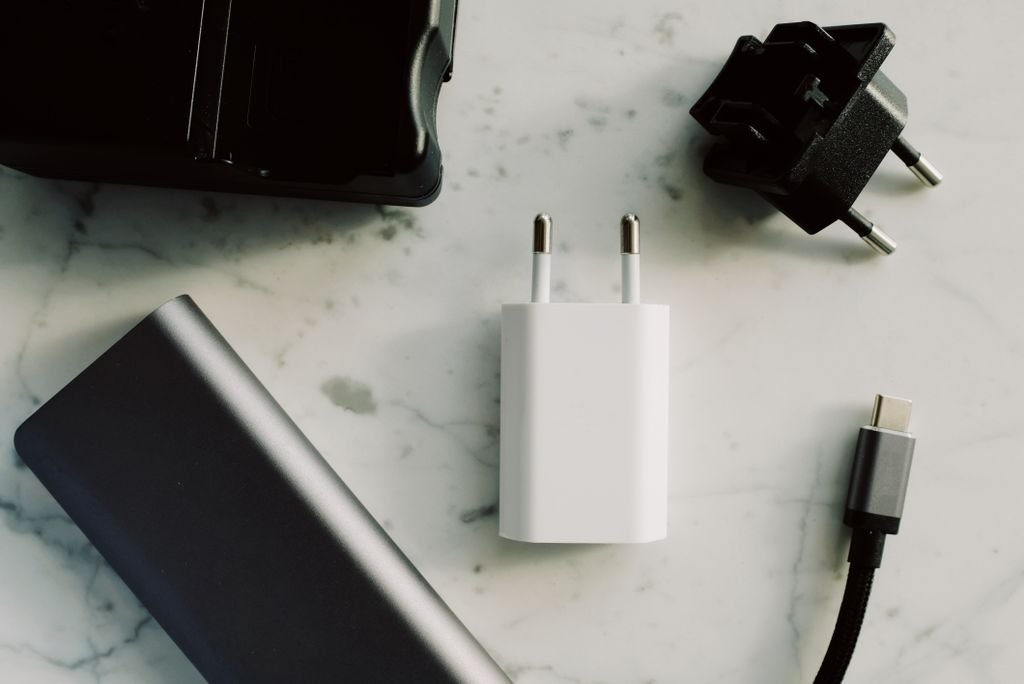 A collection of chargers, adapters and a USB-C cable laid out on a surface