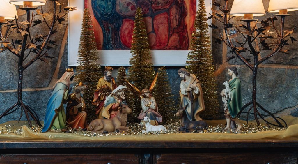 Presepe allestito su una mensola con alberelli e candele