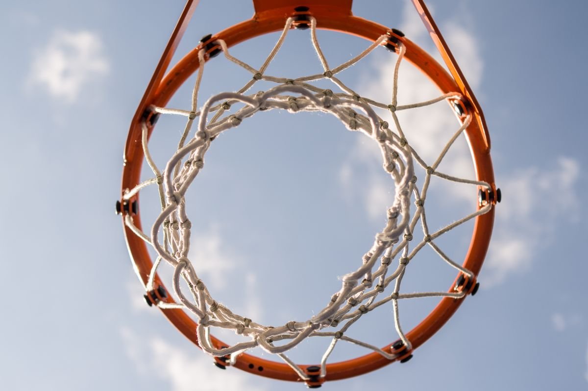 Basketball hoop seen from below against a blue sky