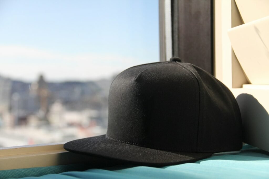Plain black snapback cap resting by a window