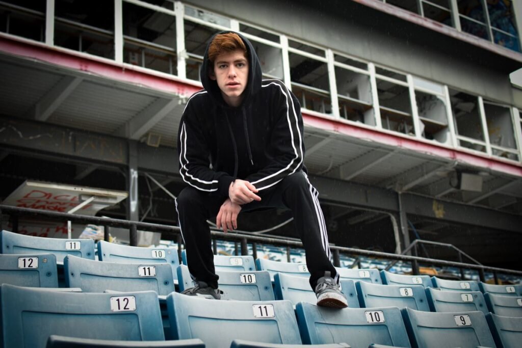 Young fan in a black hoodie sitting in the stadium stands