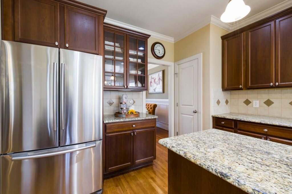 Stainless french door refrigerator with a bottom freezer drawer in a wood-cabinet family kitchen