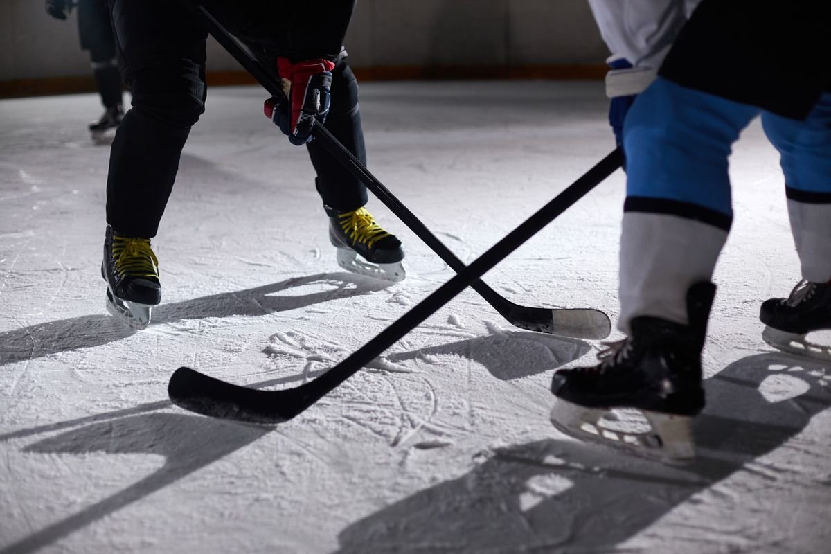 Two hockey sticks meeting at a face-off on the ice