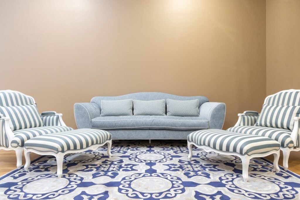 Matching sofa, armchairs and ottomans arranged as a living room set on a patterned rug