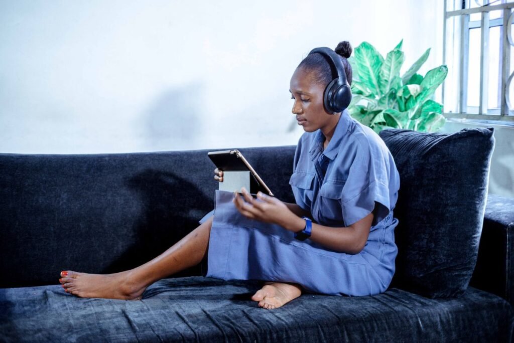 Woman on a sofa wearing headphones and reading on a tablet