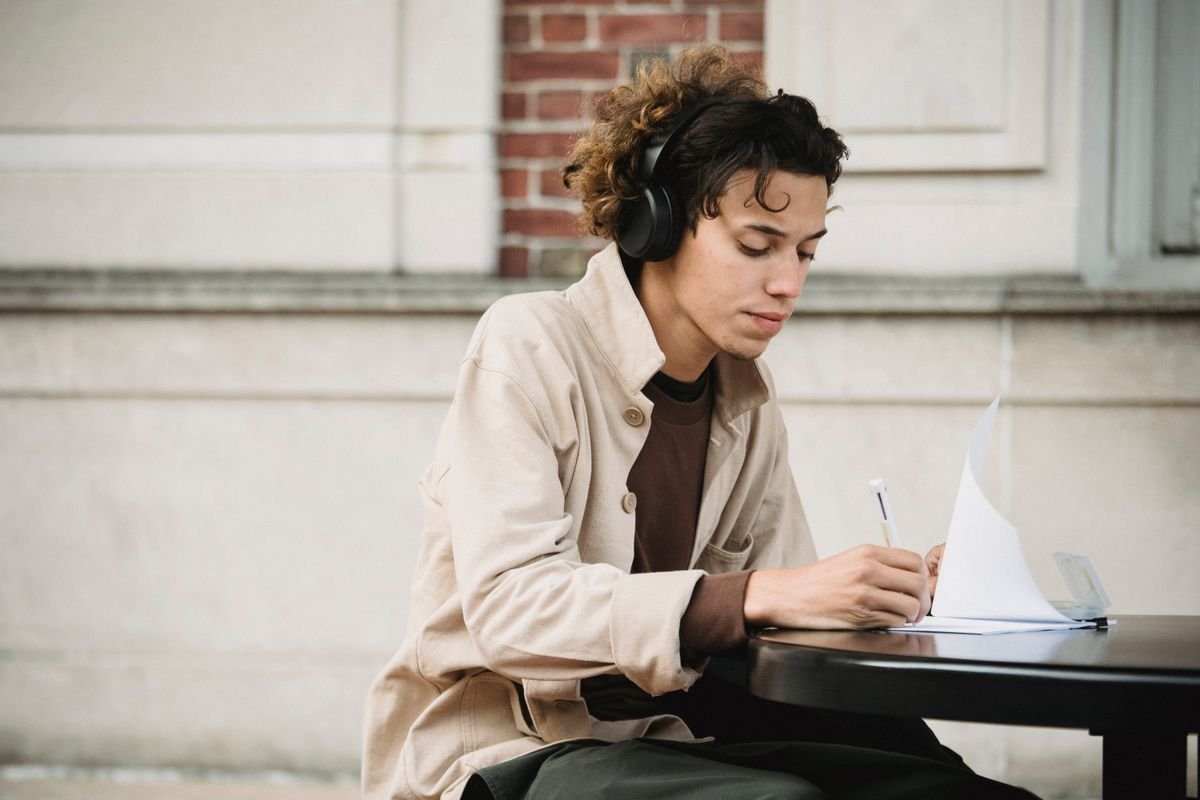 Young man wearing headphones and writing notes