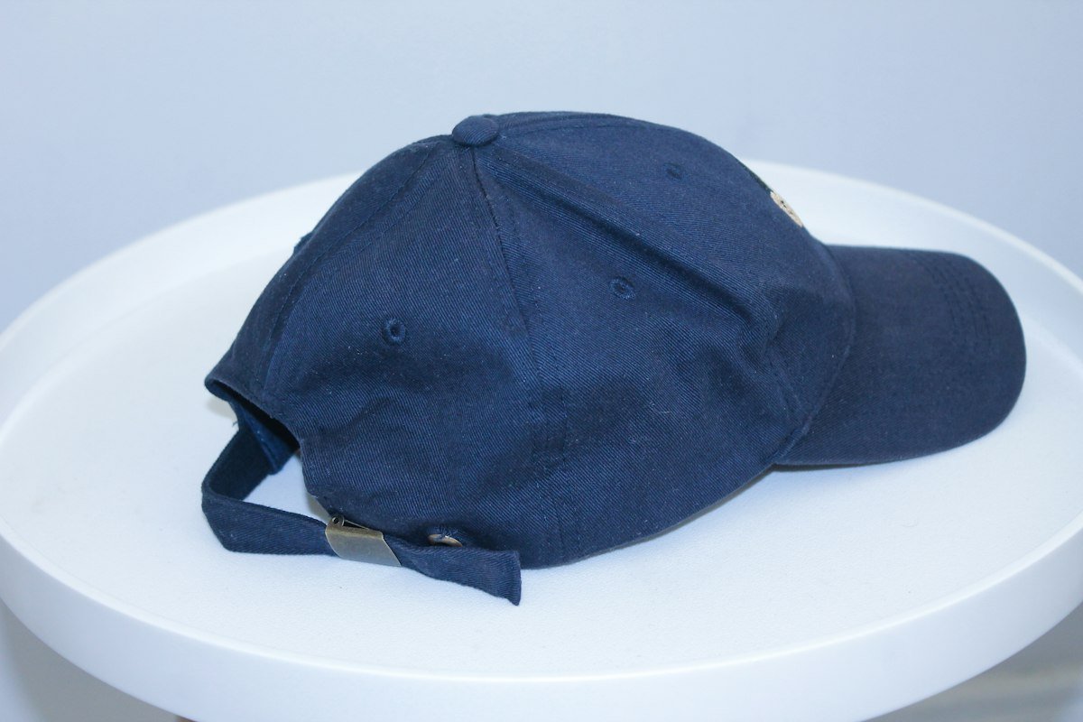 Navy strap-back baseball cap on a plain surface