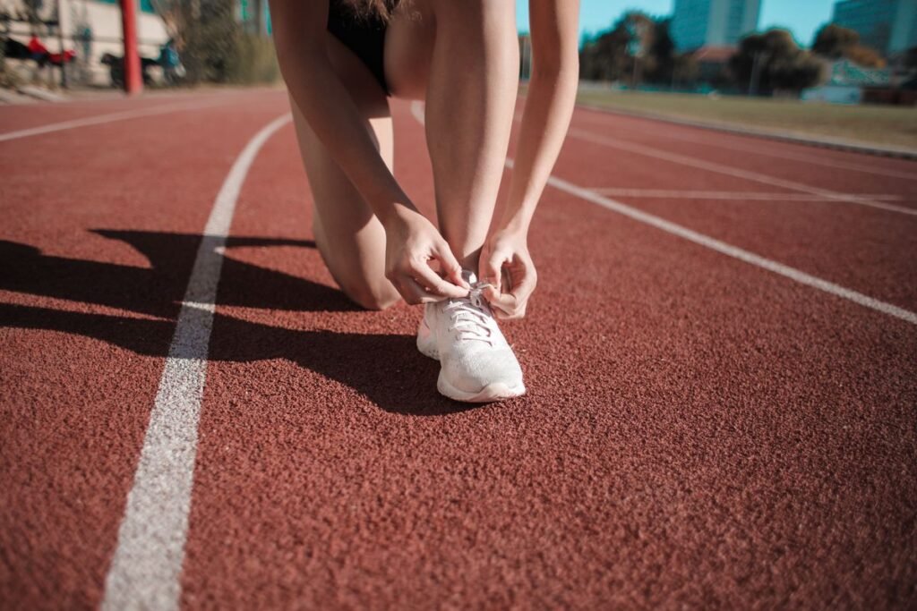 Runner tying a white running shoe on a track