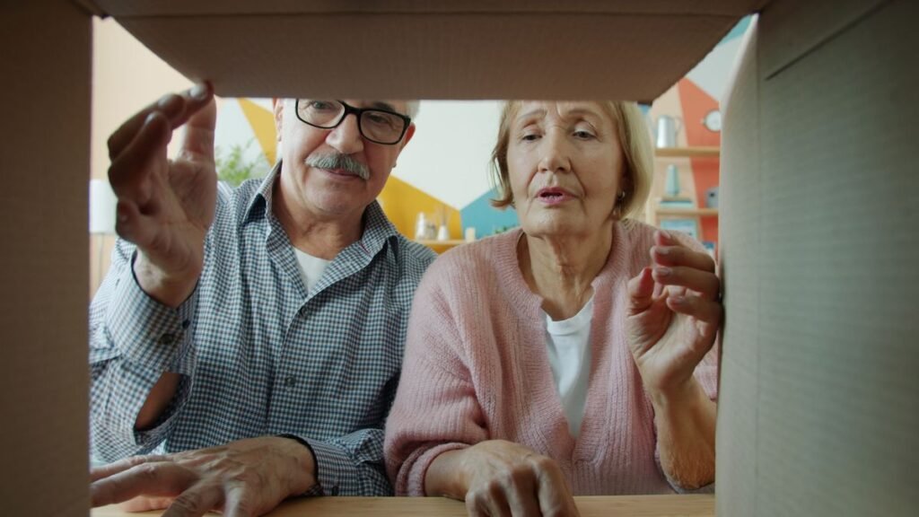 Older couple opening a cardboard moving box together in their home