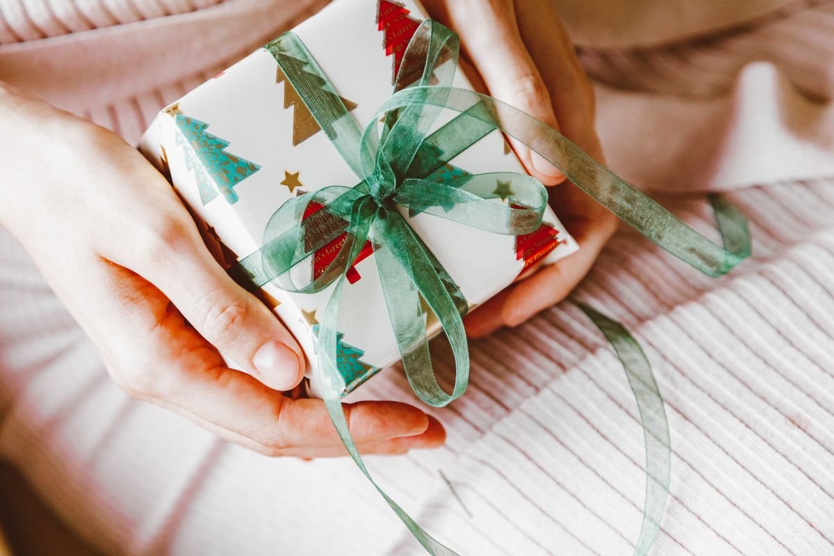 Hands holding a small wrapped gift with a green ribbon