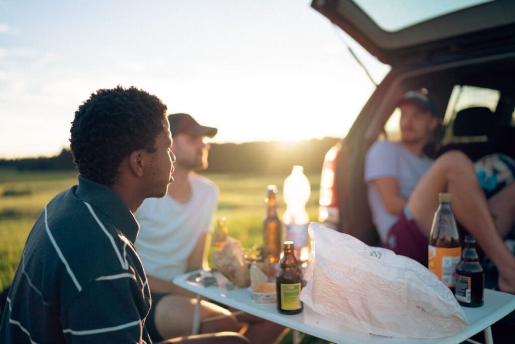 Team Coolers and Tumblers for a Better Tailgate Friends gathered at an open car tailgate at sunset